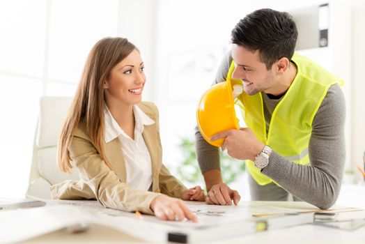 Smiling young architects discussing construction plans in office.