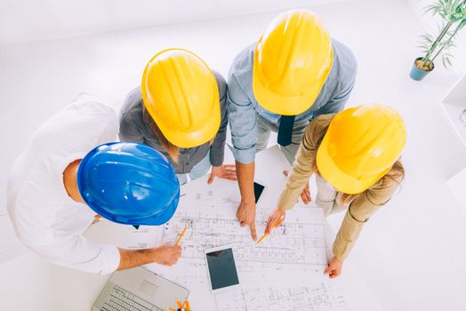 Top view of four successful architect checking the architectural plans.