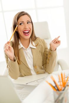 Young successful female architect sitting in the office and  thinking. Having brilliant idea for business progress.