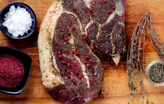 Perfect Big Raw Beef Steak with Spices, Salt Flakes and Herbs Ready to Roast closeup on Wooden background