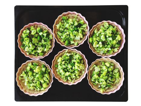 Broccoli pies on a baking tray. Cooking process. Isolated on white.