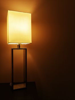 Illuminated modern table lamp in a dark room.