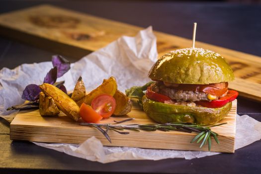 Concept: healthy food. Gourmet homemade burger with garnish and ingredients on the dark background.