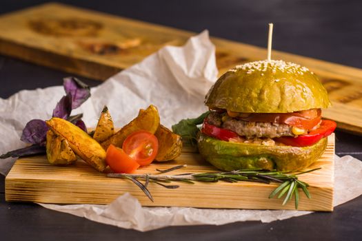 Concept: healthy food. Gourmet homemade burger with garnish and ingredients on the dark background.