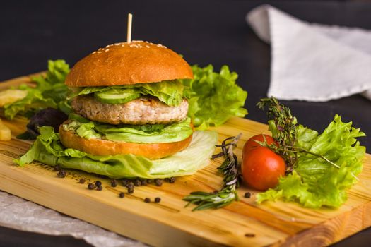 Concept: healthy food. Gourmet homemade burger with garnish and ingredients on the dark background.