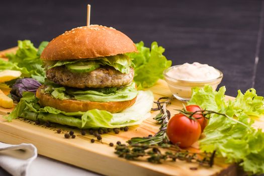 Concept: healthy food. Gourmet homemade burger with garnish and ingredients on the dark background.