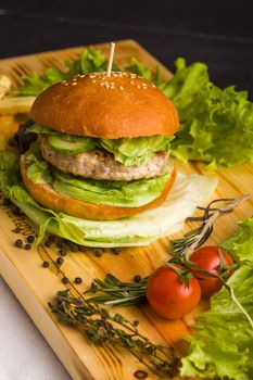 Concept: healthy food. Gourmet homemade burger with garnish and ingredients on the dark background.