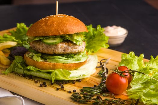 Concept: healthy food. Gourmet homemade burger with garnish and ingredients on the dark background.