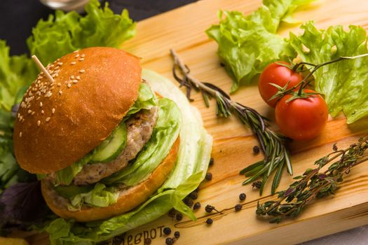 Concept: healthy food. Gourmet homemade burger with garnish and ingredients on the dark background.