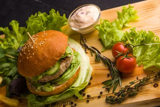 Concept: healthy food. Gourmet homemade burger with garnish and ingredients on the dark background.