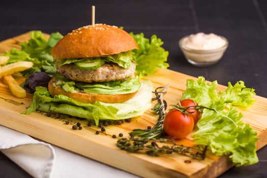 Concept: healthy food. Gourmet homemade burger with garnish and ingredients on the dark background.