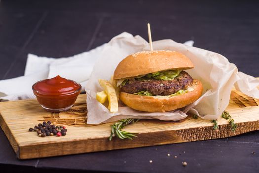 Concept: healthy food. Gourmet homemade burger with garnish and ingredients on the dark background.