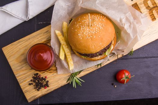 Concept: healthy food. Gourmet homemade burger with garnish and ingredients on the dark background.