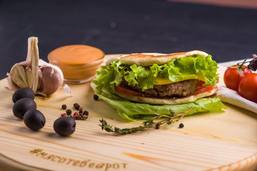 Concept: healthy food. Gourmet homemade burger with garnish and ingredients on the dark background.