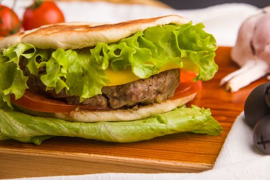 Concept: healthy food. Gourmet homemade burger with garnish and ingredients on the dark background.