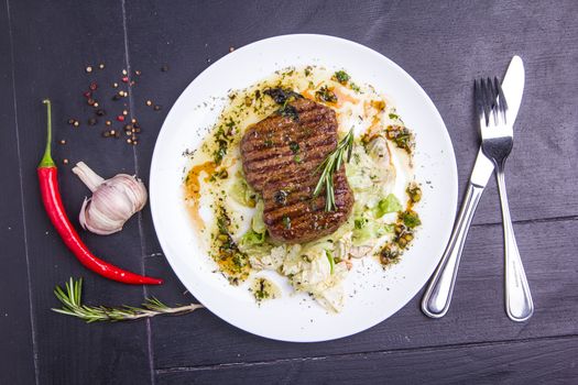 Concept: healthy food. Homemade grilled veal steak and vegetables on a plate with ingredients and cutlery around