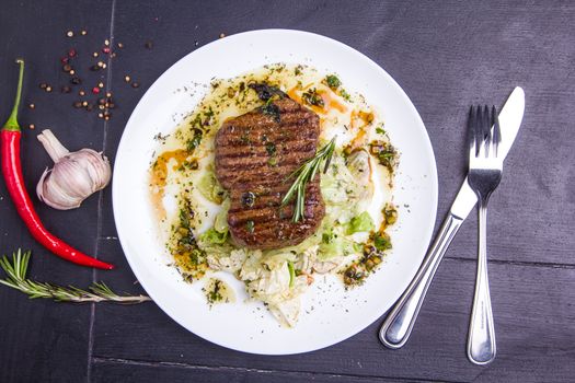 Concept: healthy food. Homemade grilled veal steak and vegetables on a plate with ingredients and cutlery around