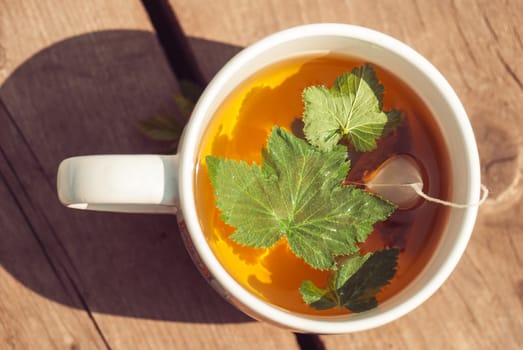 Top view of tea with currant leaf in white cup