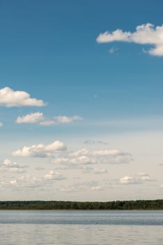 Beautiful summer lake, on  background of forest and cloudy sky.