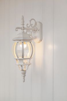 the metal white forged candelabrum on a white wooden wall