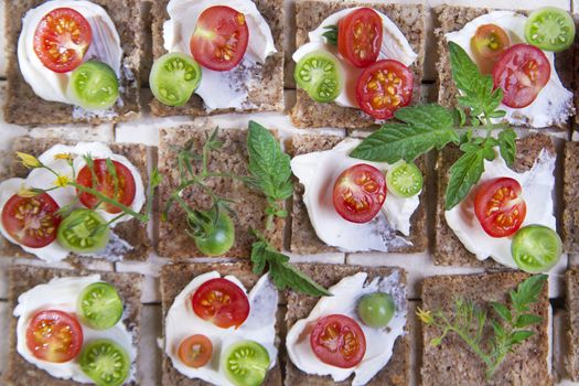 Presentation of slices of wholemeal bread with cheese and cherry tomatoes 