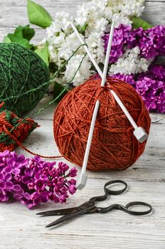  clew of wool yarn for knitting and branches of lilac blossoms