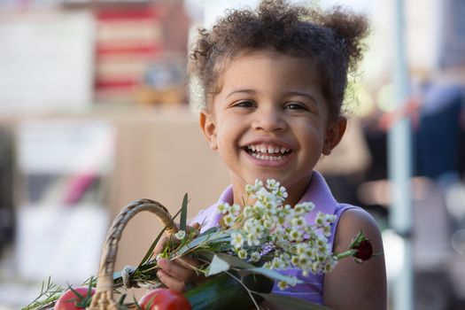 Cute young girl with basket of produce at farmers market