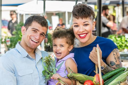 Smiling family with basket of produce at farmers market