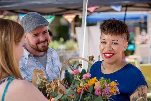 Attractive couple purchases flowers at outdoor farmers market