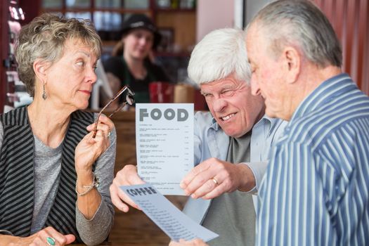 Mature man has difficulty reading menu in a cafe