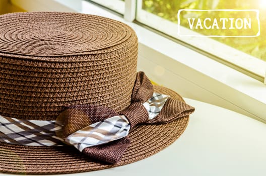 The brown woman hat on white table near the window with daylight. Vacation concept.