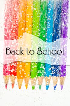 Back to school concept. Colorful wooden pencils in soda water with bubbles on white background.