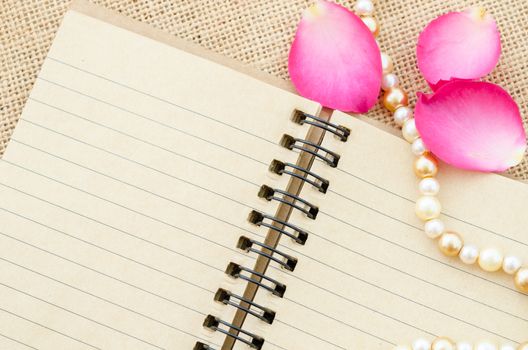 Vintage blank open old diary with flower on sack background.