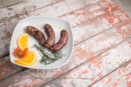 Sausages on dish with olive oil and slice orange