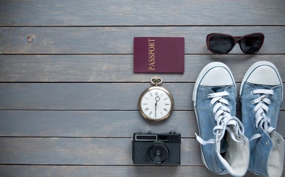 Closeup of travel items on a wooden background with passport, camera and shoes 