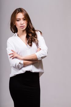 Asian American businesswoman with crossed arms looking at camera on gray background