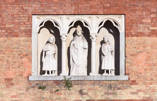 In the picture three statues, located in the center the statue of Saint Ambrose, Milan, Italy.