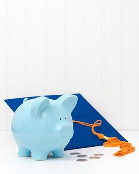 Blue piggy bank and graduation cap.  Conveys the concept of the cost of higher education.