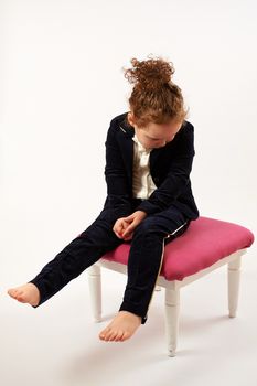 Little girl in black suit sitting and pouting