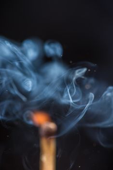 Match with smoke and fire on  the black background.  copyspace