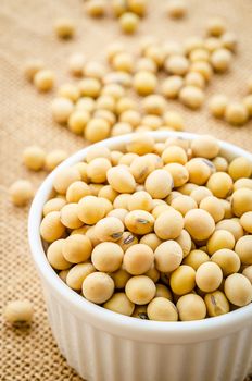Soy beans in white bowl on sack background.
