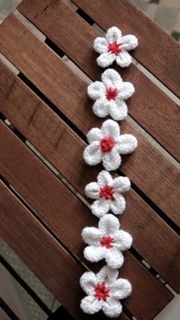 Group of handmade product for mother day, white daisy flower on wood background, make by knit from yarn