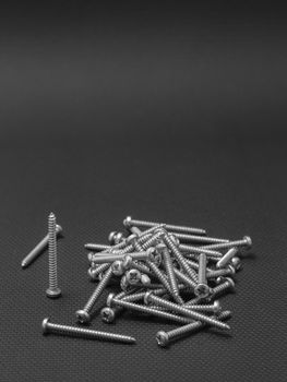 Screws located on a black background to understand an industrial concept