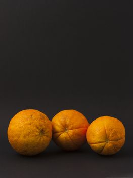 Three oranges on a black background to understand a concept for healthy eating