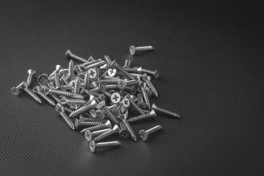 Screws located on a black background to understand an industrial concept