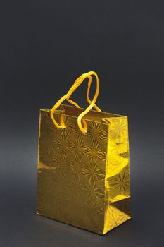 Shiny yellow gift bag isolated on a black background