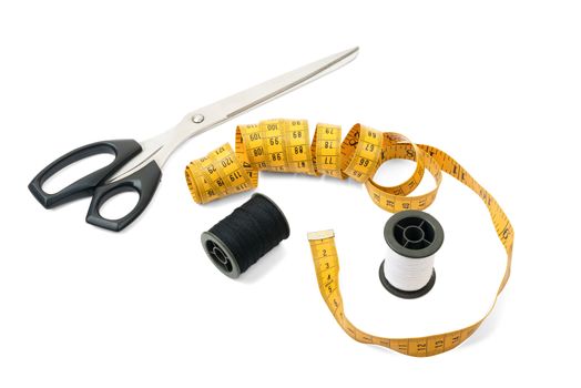 Sewing accessories: thread bobbin, measure tape and scissors on white background