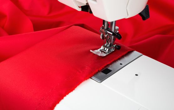 Sewing machine and red fabric isolated on white background