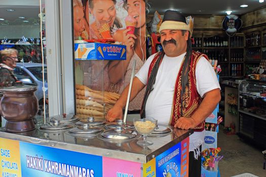 An ice cream seller, dressed in traditional turkish costume, waiting for customers.