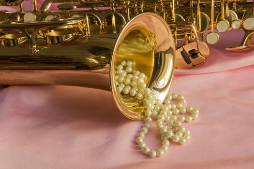 Saxophone and Pearl necklace on Pink silk fabric soft